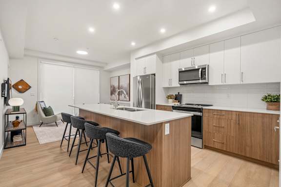 A modern kitchen with a white countertop and wooden cabinets.
