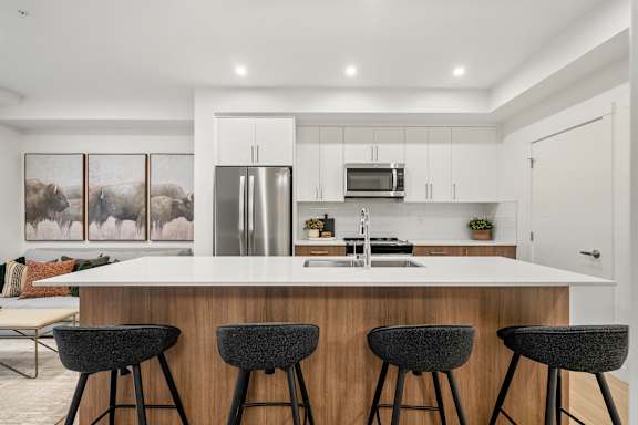 A modern kitchen with a white countertop and black bar stools.