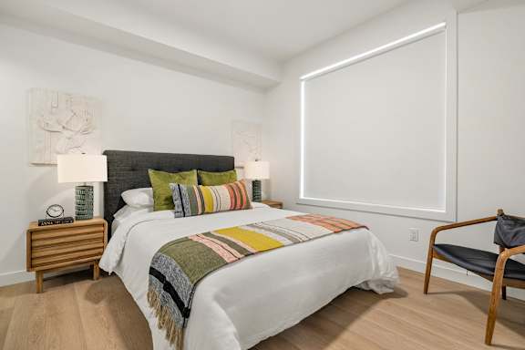 A bedroom with a large bed and a chair.