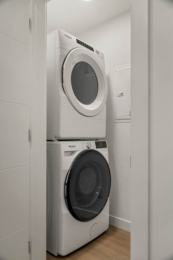 Two white front load washing machines stacked on top of each other in a laundry room.