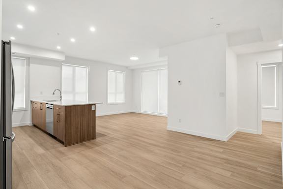 A spacious kitchen with wooden floors and white walls.