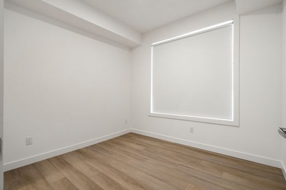 A room with a large window and wooden flooring.