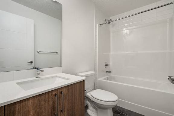 A white bathroom with a toilet, sink, and bathtub.