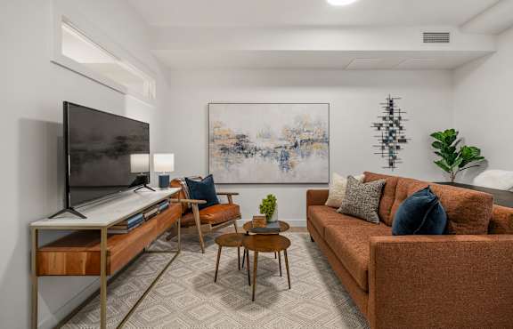 A living room with a brown couch, a television, and a painting on the wall.