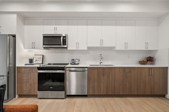 A modern kitchen with a refrigerator, microwave, oven, and sink.