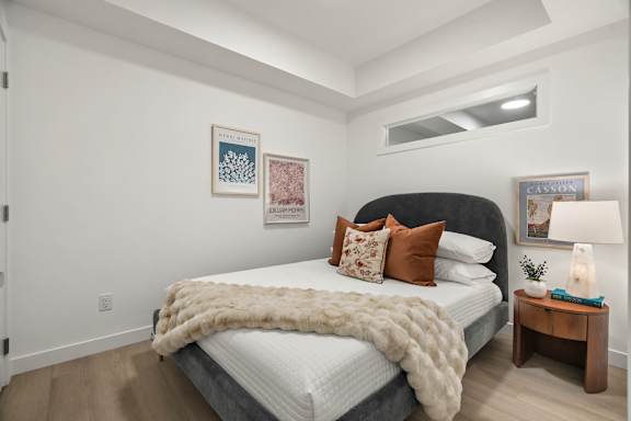 A bedroom with a bed covered in a white blanket and pillows.