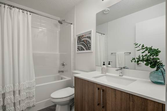A white bathroom with a toilet, sink, and shower.