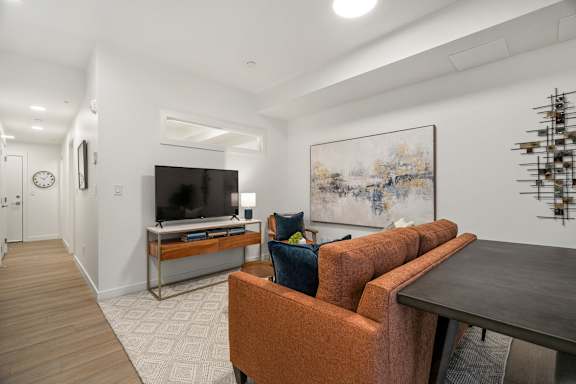 A living room with a brown sofa and a painting on the wall.