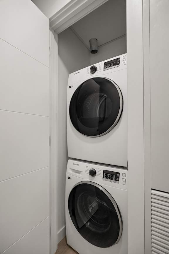 Two white front loading washing machines in a laundry room.