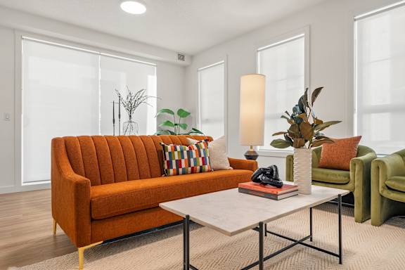 A living room with a brown sofa, a white coffee table, and a green armchair.