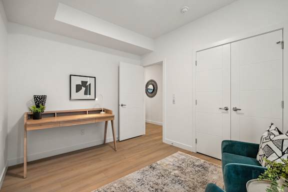 A room with a wooden bench, a rug, and a door.