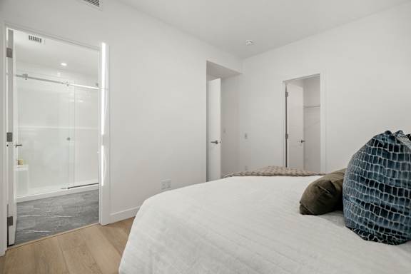 A bedroom with a large bed and a glass door leading to a bathroom.