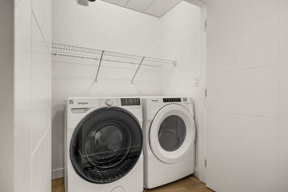 Two white front load washing machines in a laundry room.
