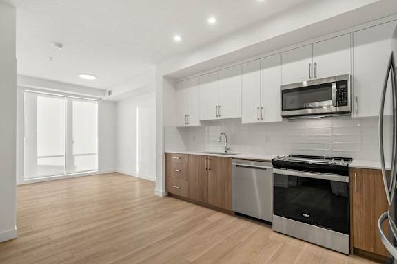 A modern kitchen with wooden floors and stainless steel appliances.