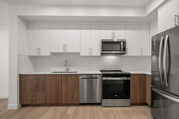 A modern kitchen with a stainless steel refrigerator, microwave, and dishwasher.