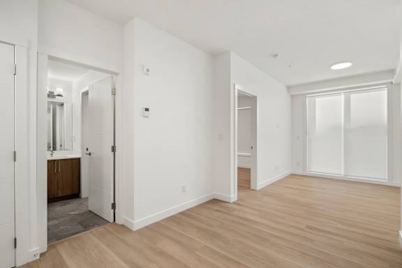 A spacious room with wooden floors and white walls.
