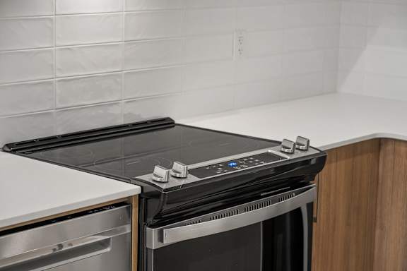A modern black stove top oven with a digital display and knobs is installed in a kitchen.