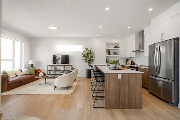 A modern kitchen with a refrigerator, stove, and island with a countertop and chairs.