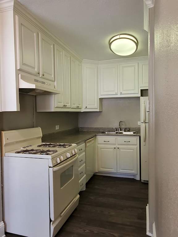 A kitchen with white appliances and cabinets.