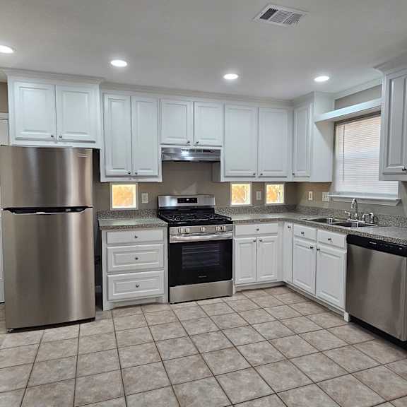 A kitchen with white cabinets and a stainless steel refrigerator.