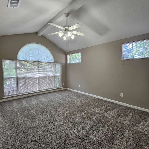 A ceiling fan hangs from the ceiling in a room with a skylight.