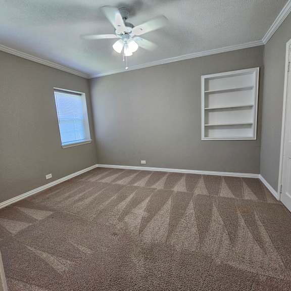 A room with a carpeted floor and a ceiling fan.