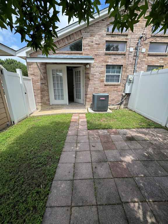 A brick house with a white fence and a green lawn.
