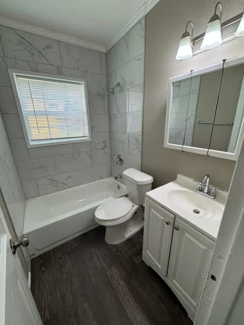 A bathroom with a white tub, toilet, and sink.