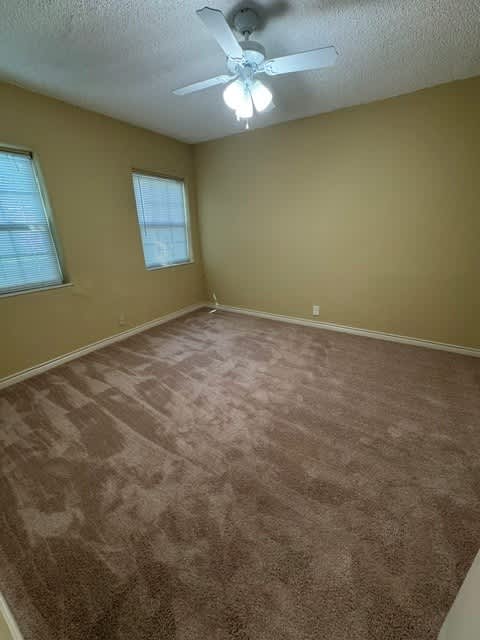 A room with a carpeted floor and a ceiling fan.