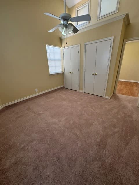 A room with a ceiling fan and three white doors.