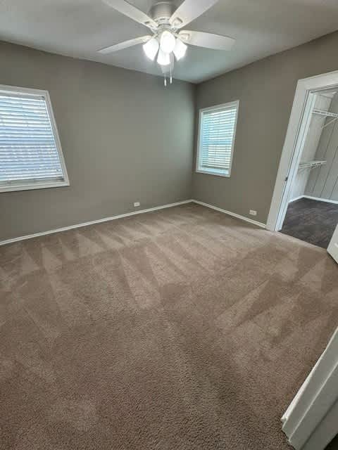 A room with a carpeted floor and a ceiling fan.