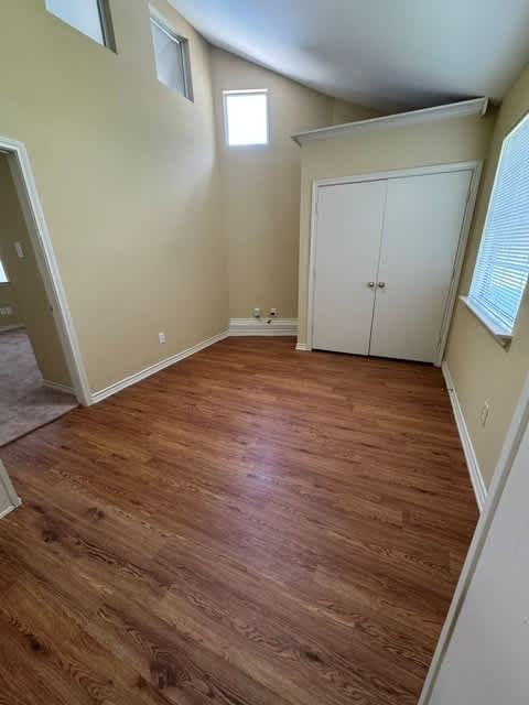 A room with a white door and wooden flooring.