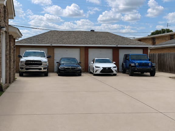 Four cars are parked in a driveway in front of a house.