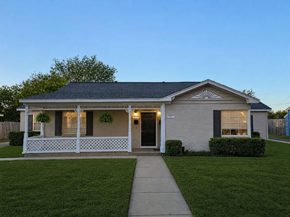 A small house with a porch and a front yard.