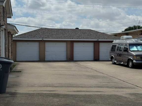 A car is parked in front of a house with three garage doors.