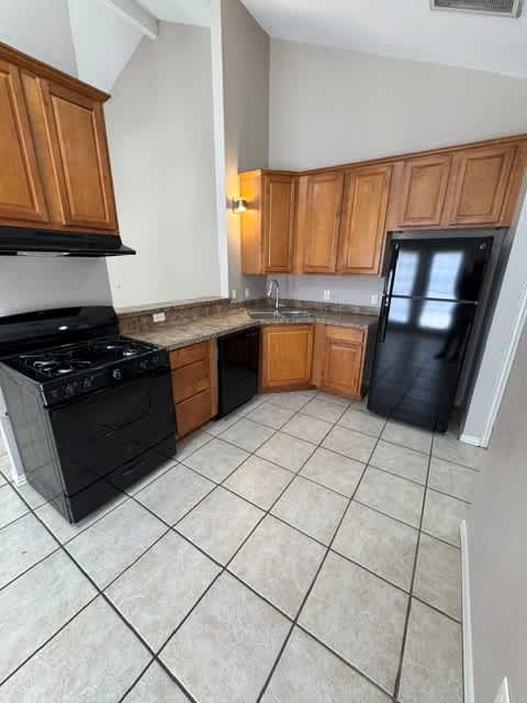 A kitchen with black appliances and wooden cabinets.