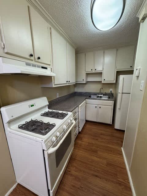 A small kitchen with a white stove and cabinets.