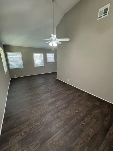 A room with a ceiling fan and wooden flooring.