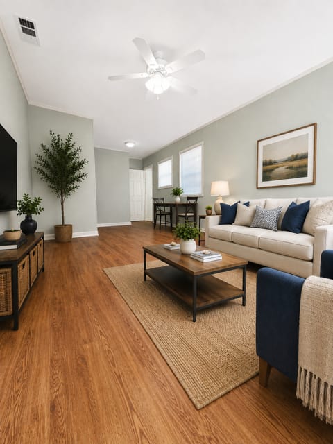 A living room with a white couch and a wooden floor.