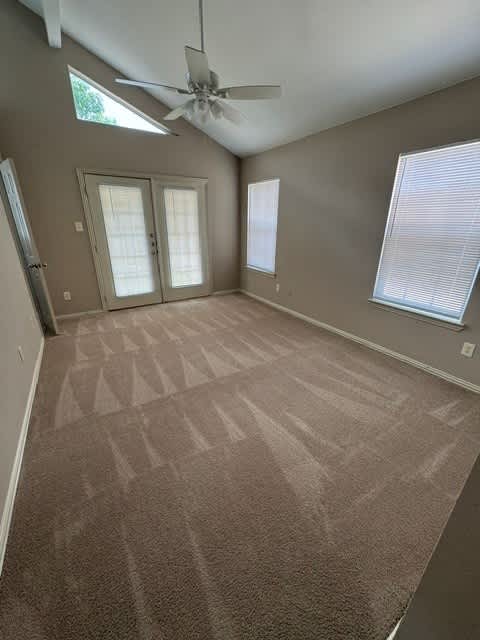 A room with a carpeted floor and a ceiling fan.