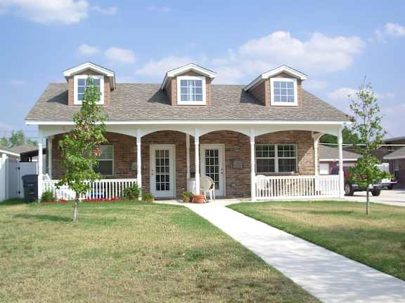 A house with a white picket fence and a tree in front.