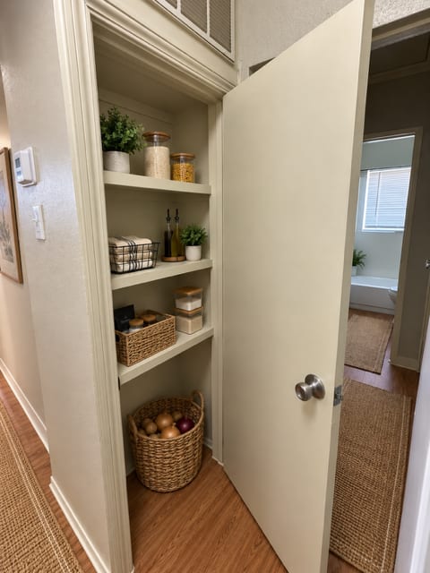 A white door is open to a hallway with a basket of fruit on the floor.