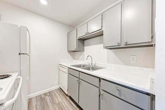 A kitchen with white cabinets and a white fridge.