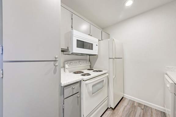 A small kitchen with a white fridge, microwave, and stove.