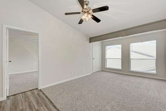 A room with a ceiling fan and a window with blinds.