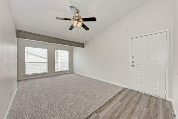 A room with a ceiling fan and a carpeted floor.