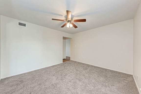 A room with a ceiling fan and carpeted floor.