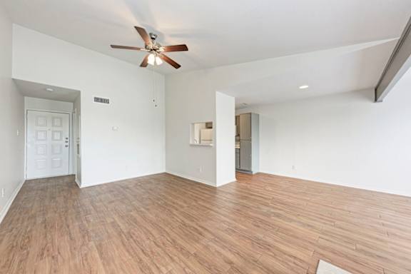 A room with a ceiling fan and wooden flooring.