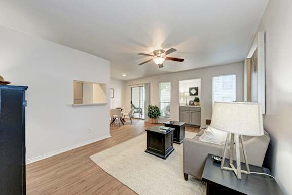 A living room with a ceiling fan and a grey couch.