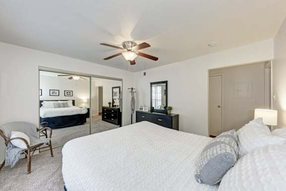 A bedroom with a large bed and a ceiling fan.